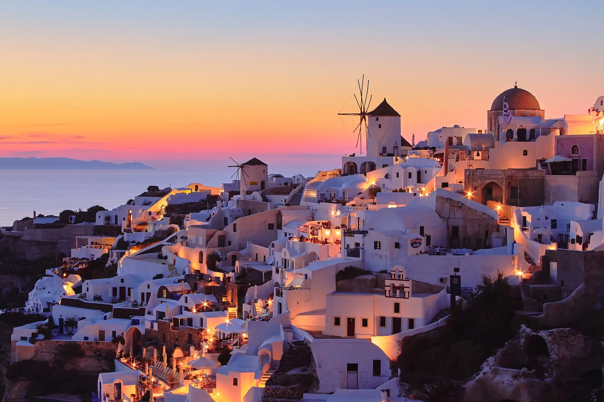 Oia at sunset with a windmill and glowing sky