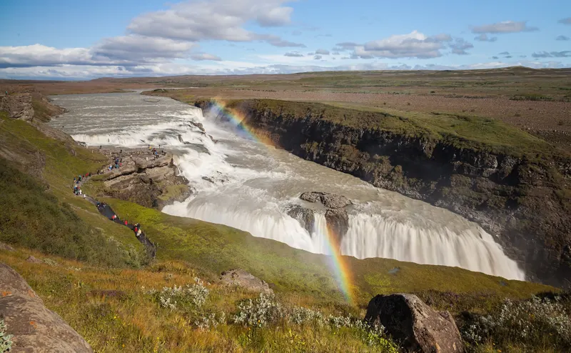 Gullfoss waterfall pouring into a canyon under a rainbow